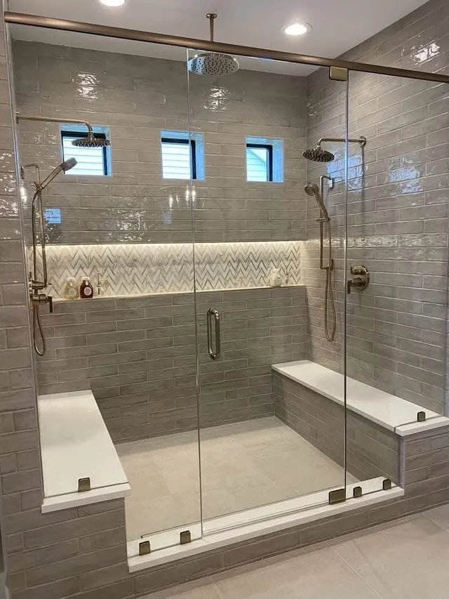Große Dusche mit gefliester Sitzbank, Mosaikband und Glasfront